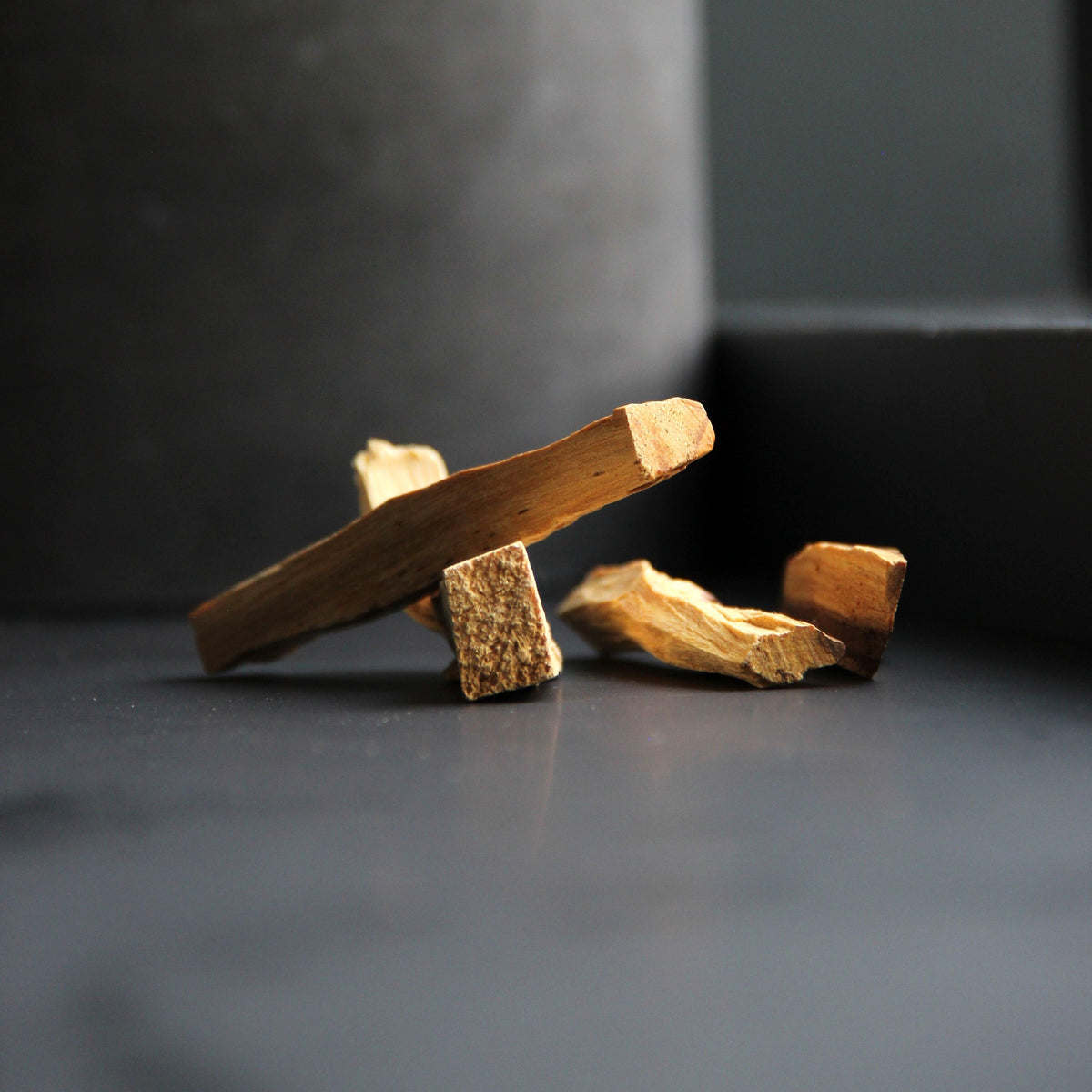 Fünf Stücke Palo Santo Holz auf dunklem Untergrund im warmen Seitenlicht