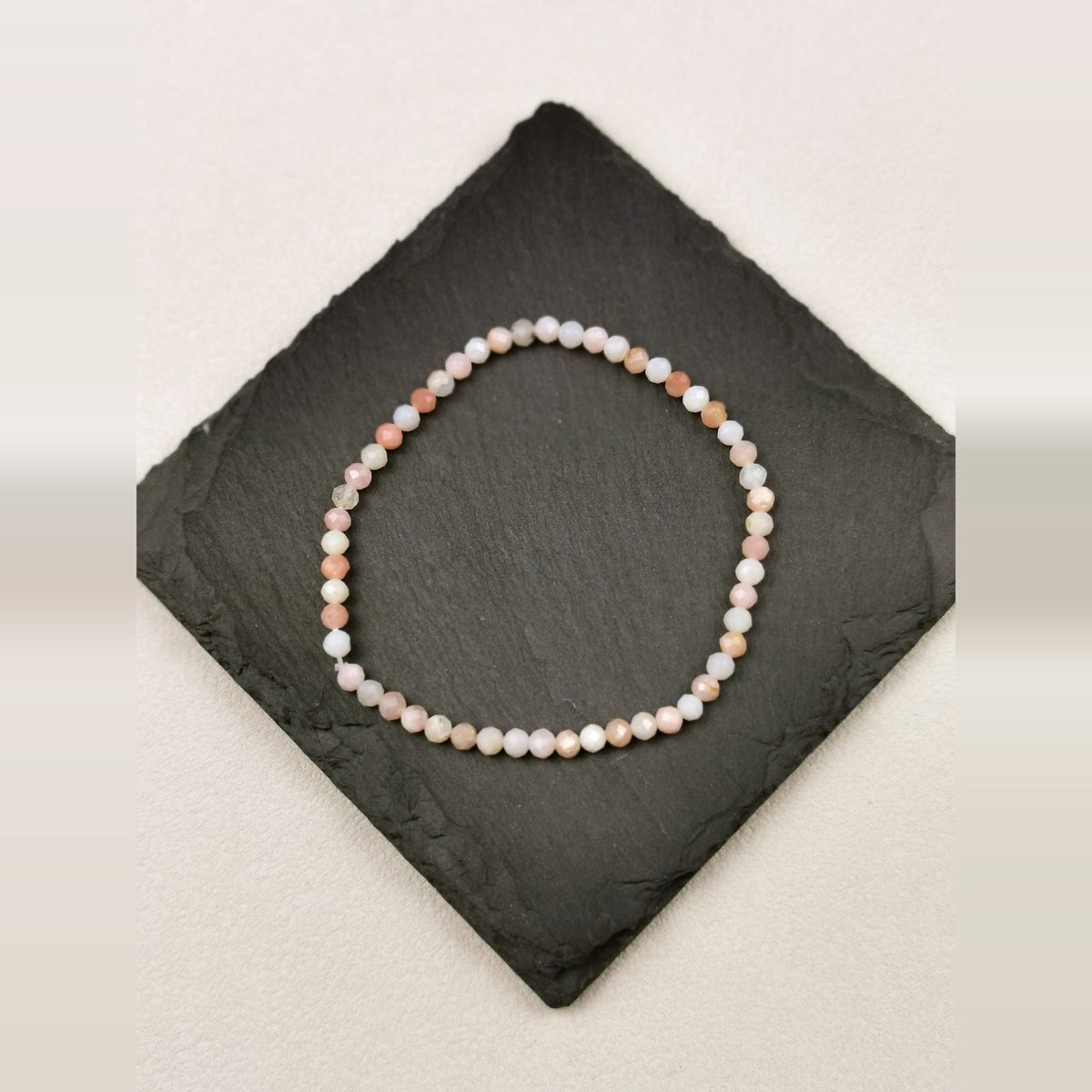 Armband aus facettierten Andenopalperlen in Rosé und Apricot mit 4 mm auf Schieferplatte