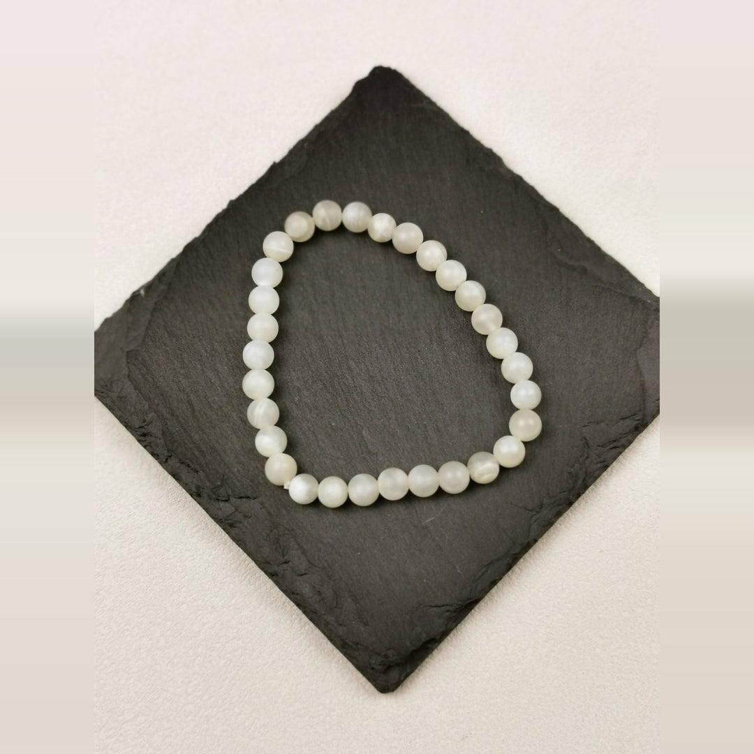 Armband aus runden cremeweißen Mondsteinperlen mit 6 mm auf Schieferplatte