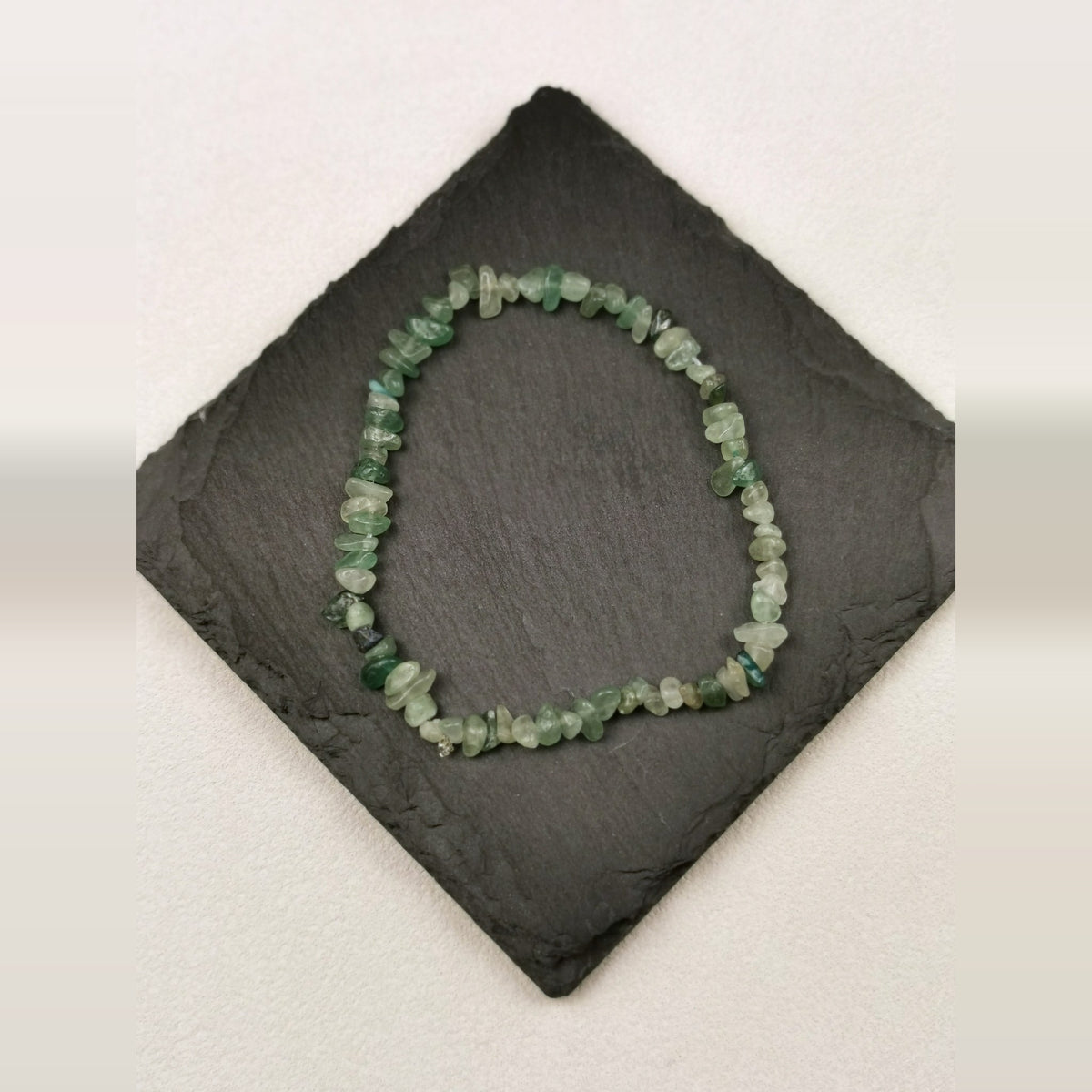 Armband aus grünen Aventurinsplittern auf Schieferplatte