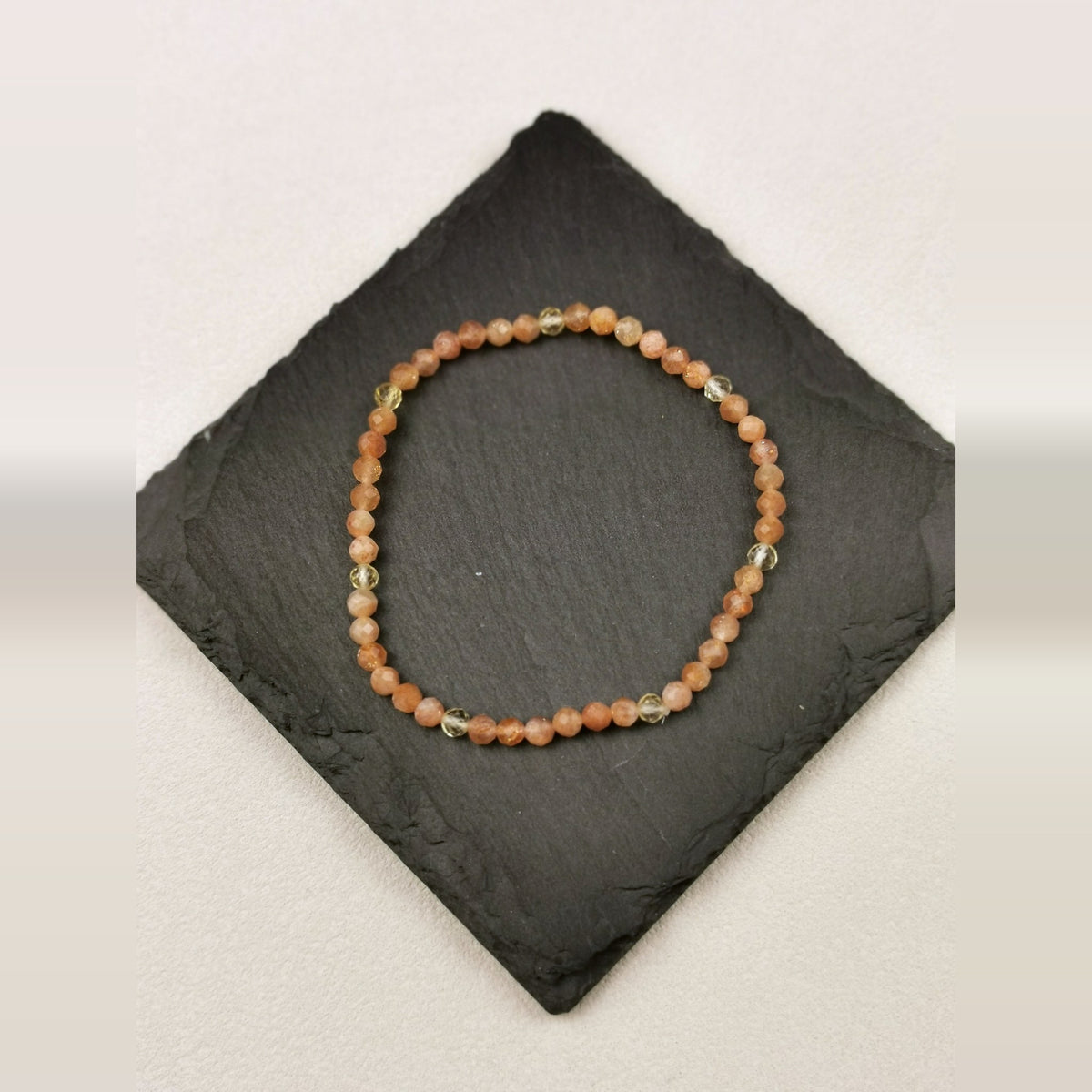 Armband aus facettierten Sonnenstein- und Citrinperlen mit 4 mm auf Schieferplatte