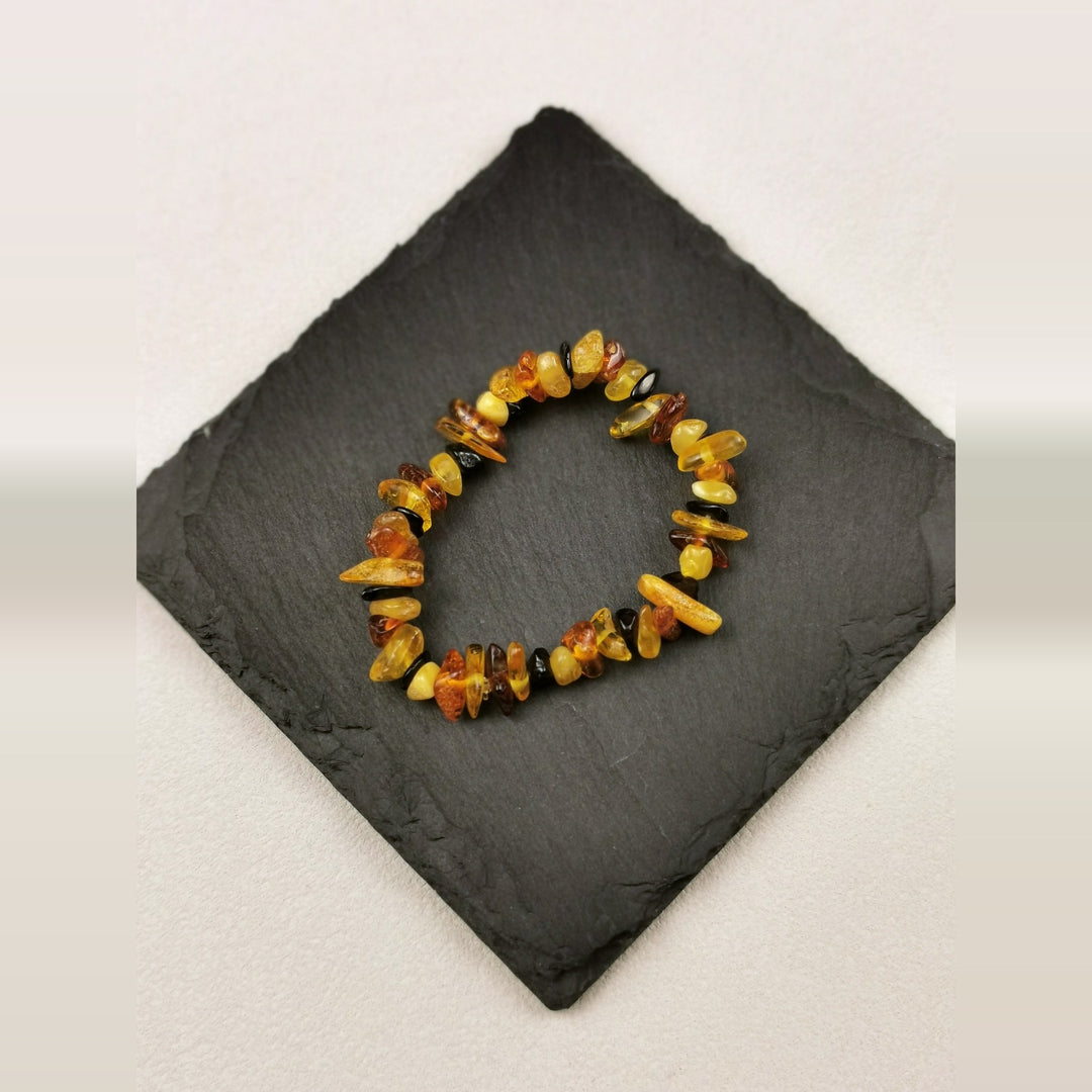Armband aus Bernsteinsplittern in Honig- und Cognactönen auf Schieferplatte