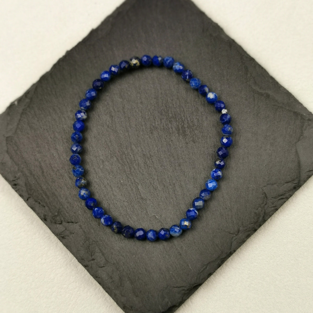 Armband aus facettierten Lapislazuliperlen in tiefem Blau mit 4 mm auf Schieferplatte