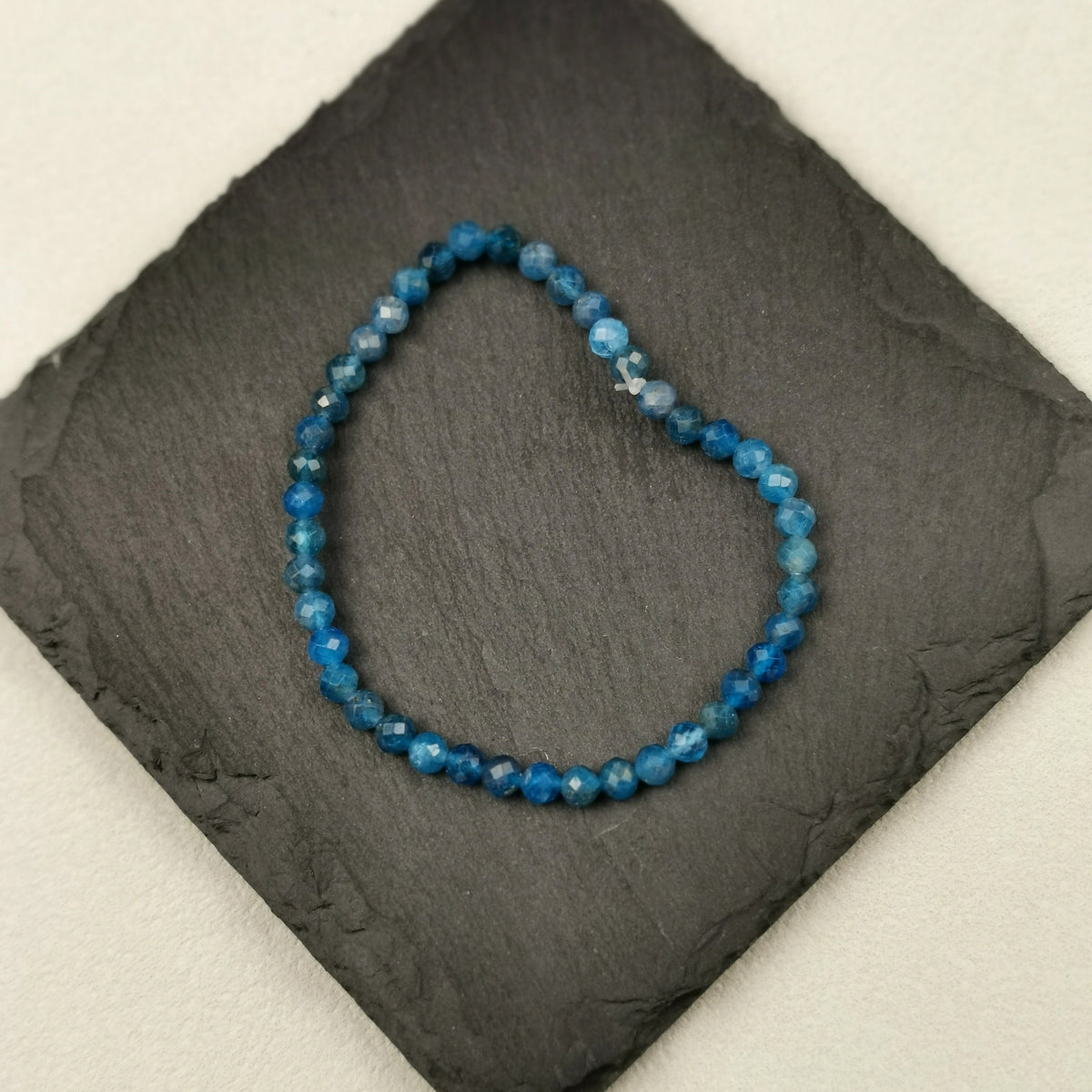 Armband aus facettierten Apatitperlen in leuchtendem Blau mit 4 mm auf Schieferplatte