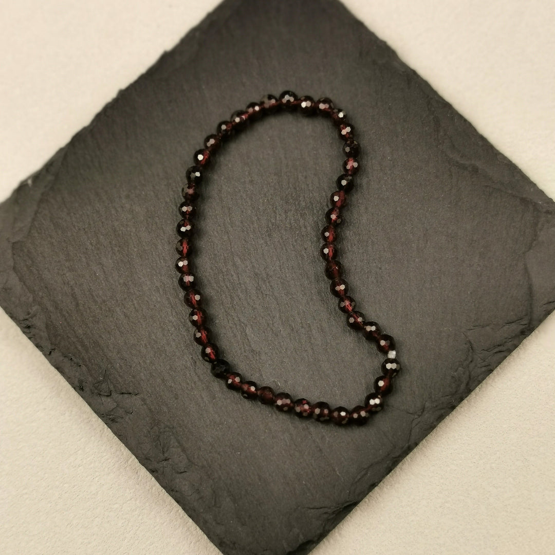 Armband aus facettierten dunkelroten Granatperlen mit 4 mm auf Schieferplatte
