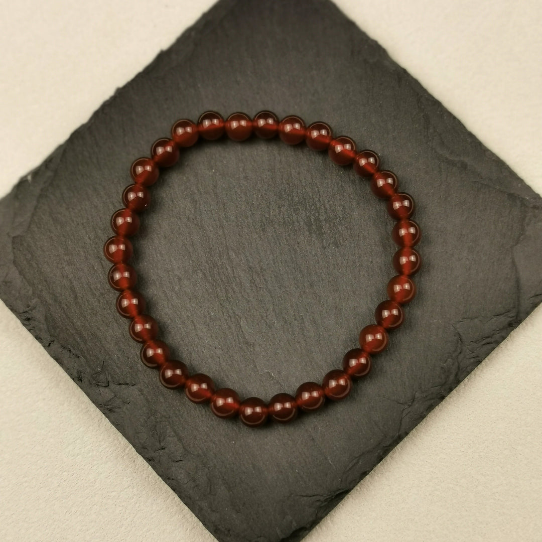 Armband aus runden Karneolperlen in Orange und Rotbraun mit 6 mm auf Schieferplatte