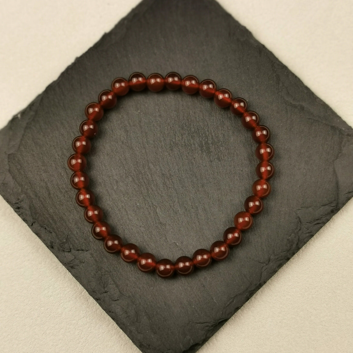 Armband aus runden Karneolperlen in Orange und Rotbraun mit 6 mm auf Schieferplatte