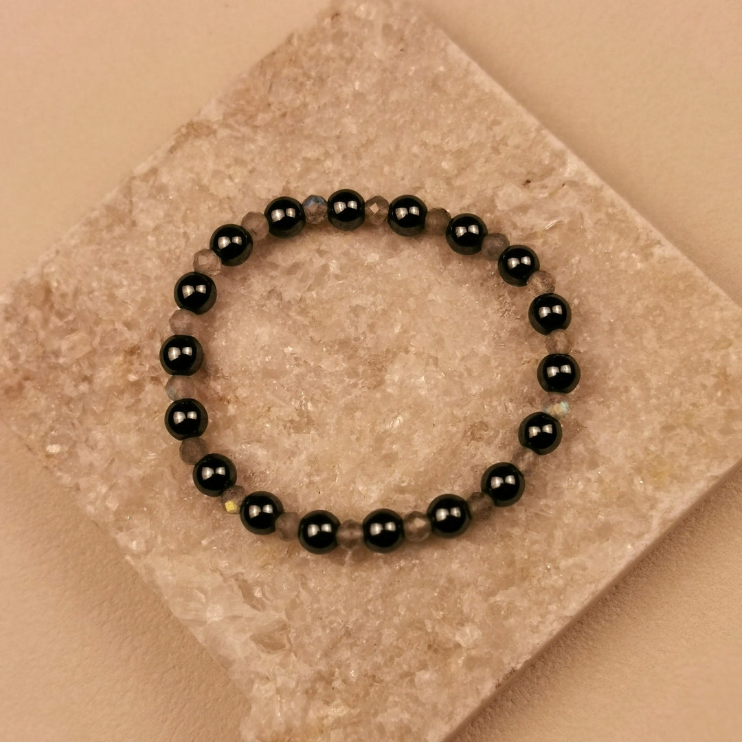 Armband aus facettiertem Labradorit und schwarzen Obsidiankugeln auf Schieferplatte
