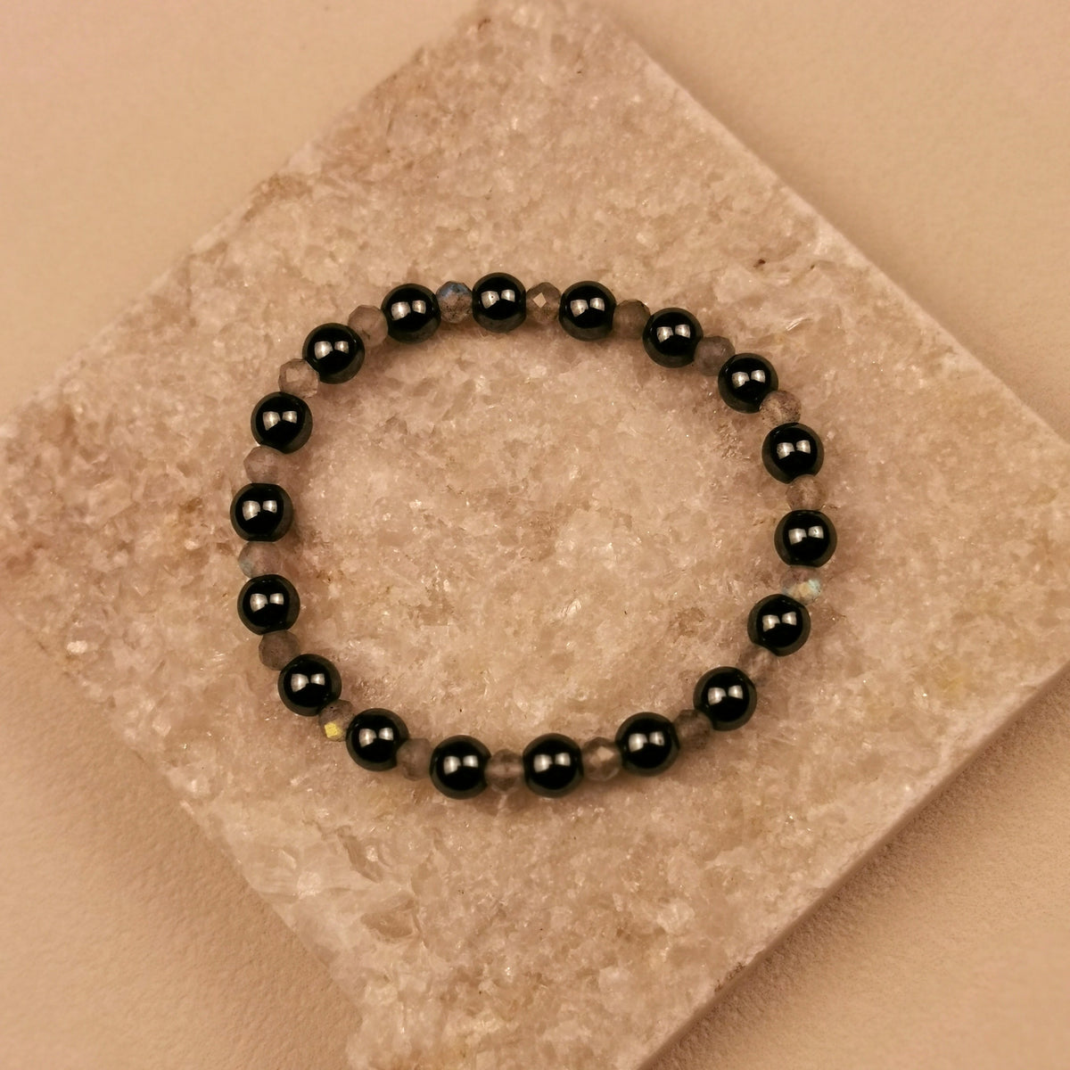 Armband aus facettiertem Labradorit und schwarzen Obsidiankugeln auf Schieferplatte
